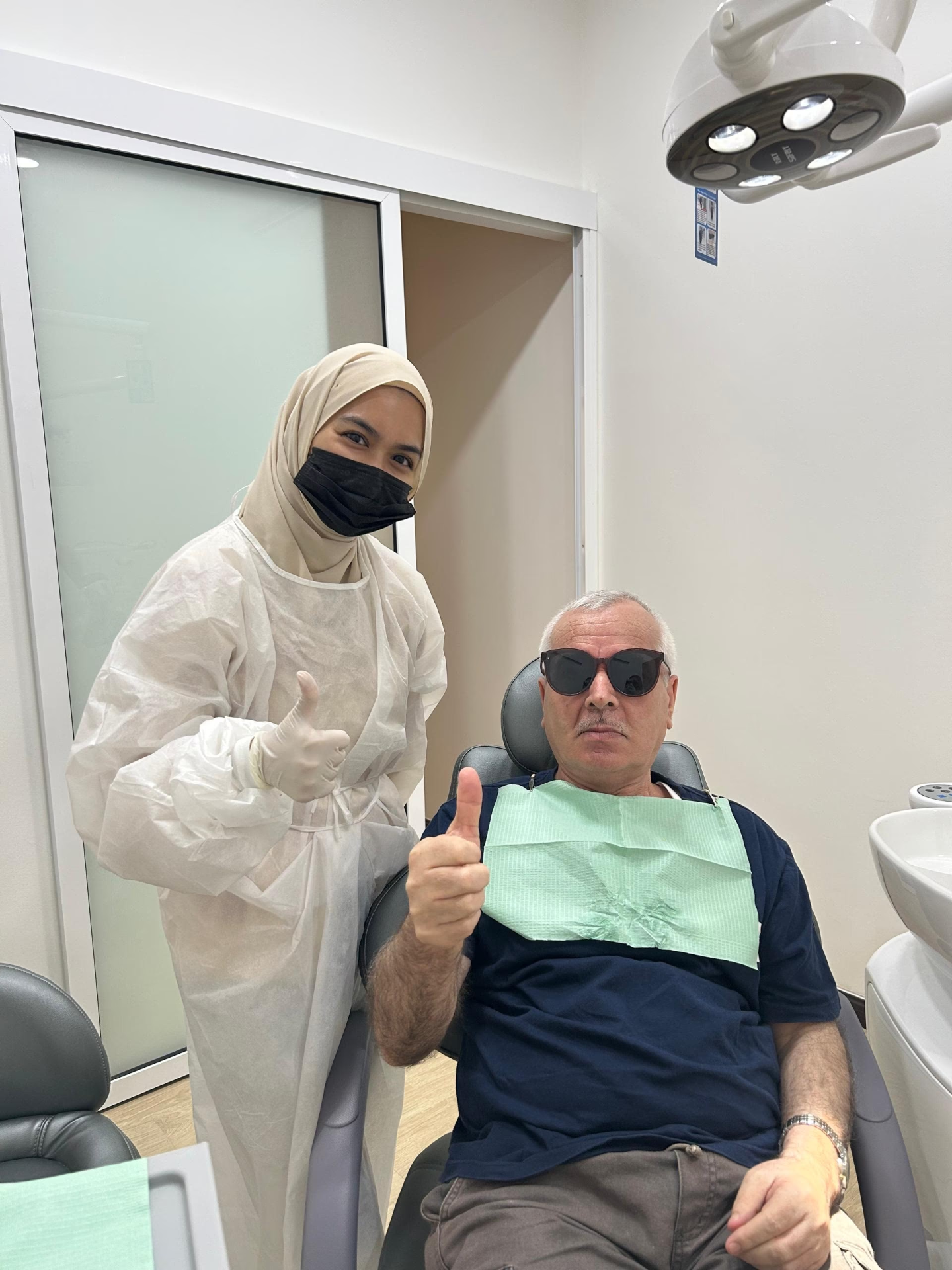 Patient and dentist giving thumbs up in the treatment room